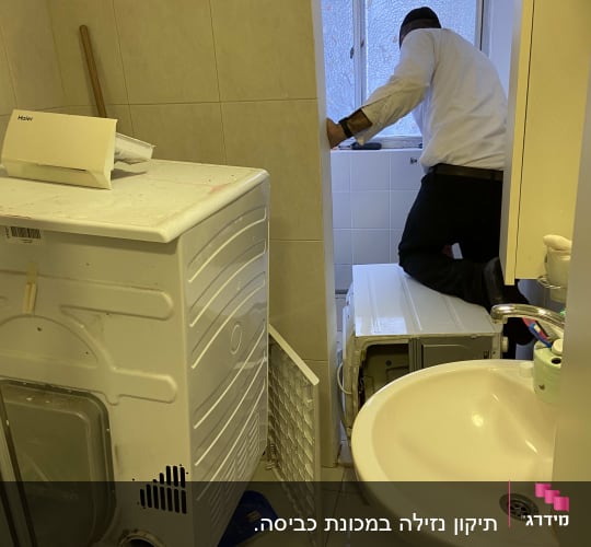 אדם עובד על מכונת כביסה בחדר אמבטיה
